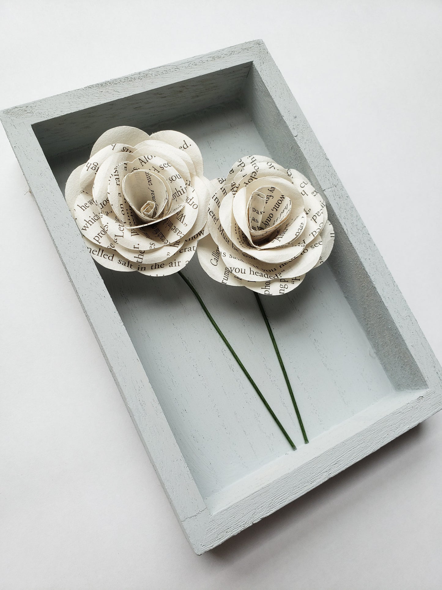 a pair of book page paper roses in a portrait shaped frame - Novel Blossoms Co