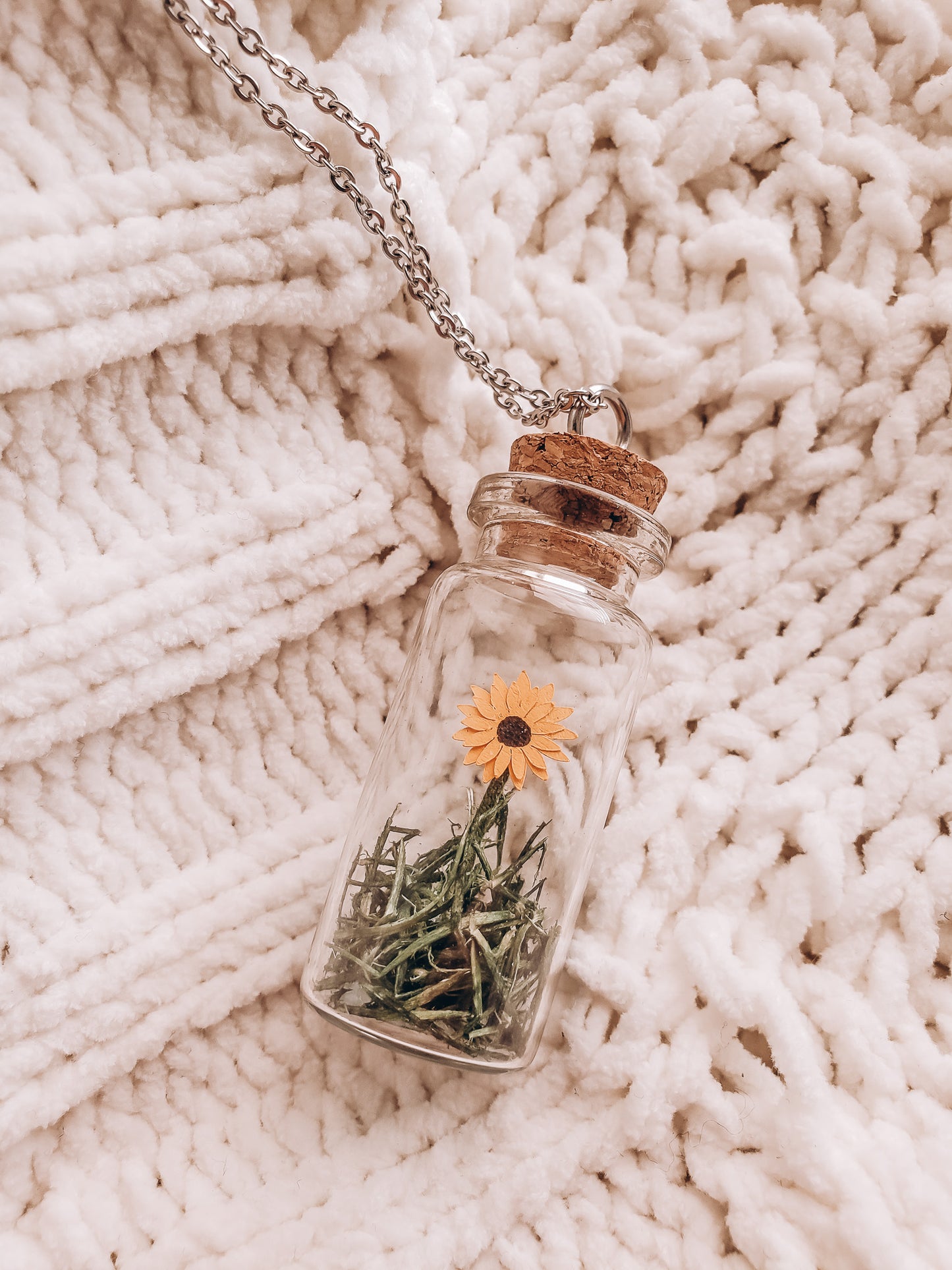 a small paper sunflower in a jar necklace lying on a cozy blanket - Novel Blossoms Co