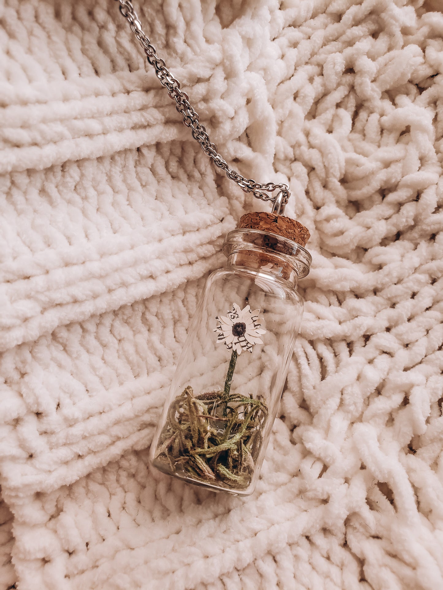 a small book page paper flower in a jar necklace lying on a cozy blanket - Novel Blossoms Co