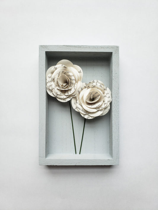 a pair of book page paper roses in a portrait shaped frame - Novel Blossoms Co