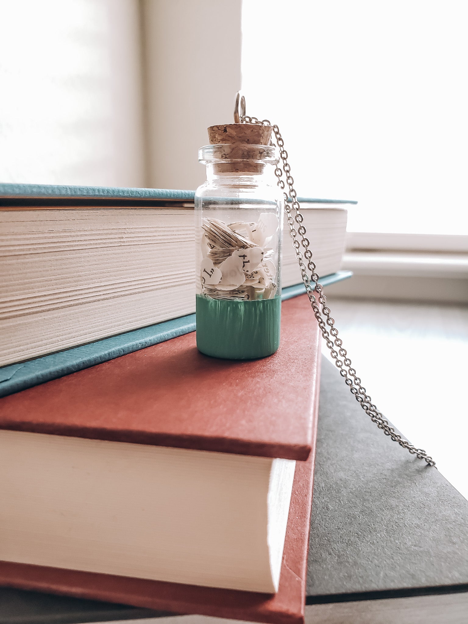 A wish jar bookish necklace sitting on a stack of books - Novel Blossoms Co