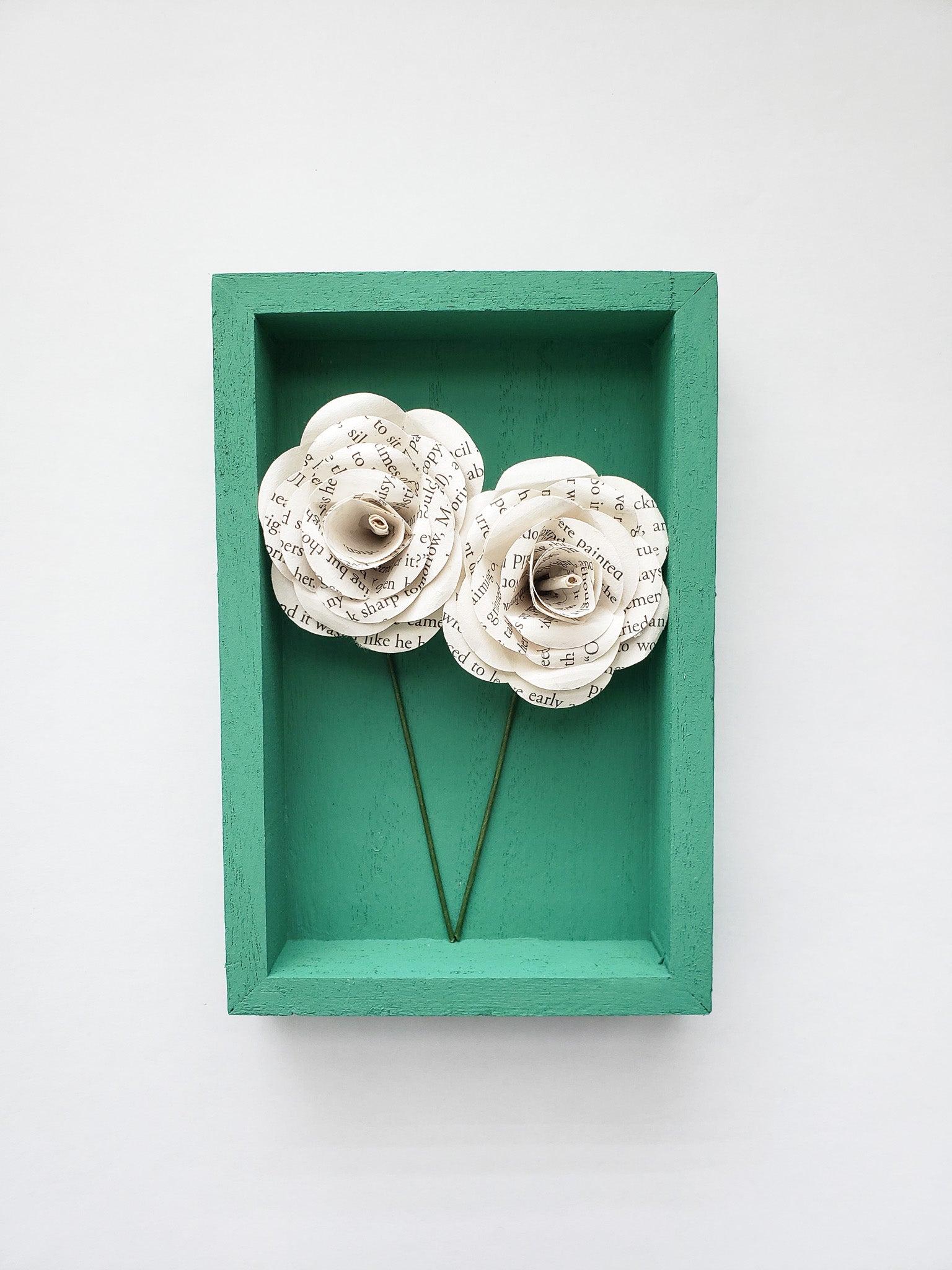 a pair of book page paper roses in a portrait shaped frame - Novel Blossoms Co