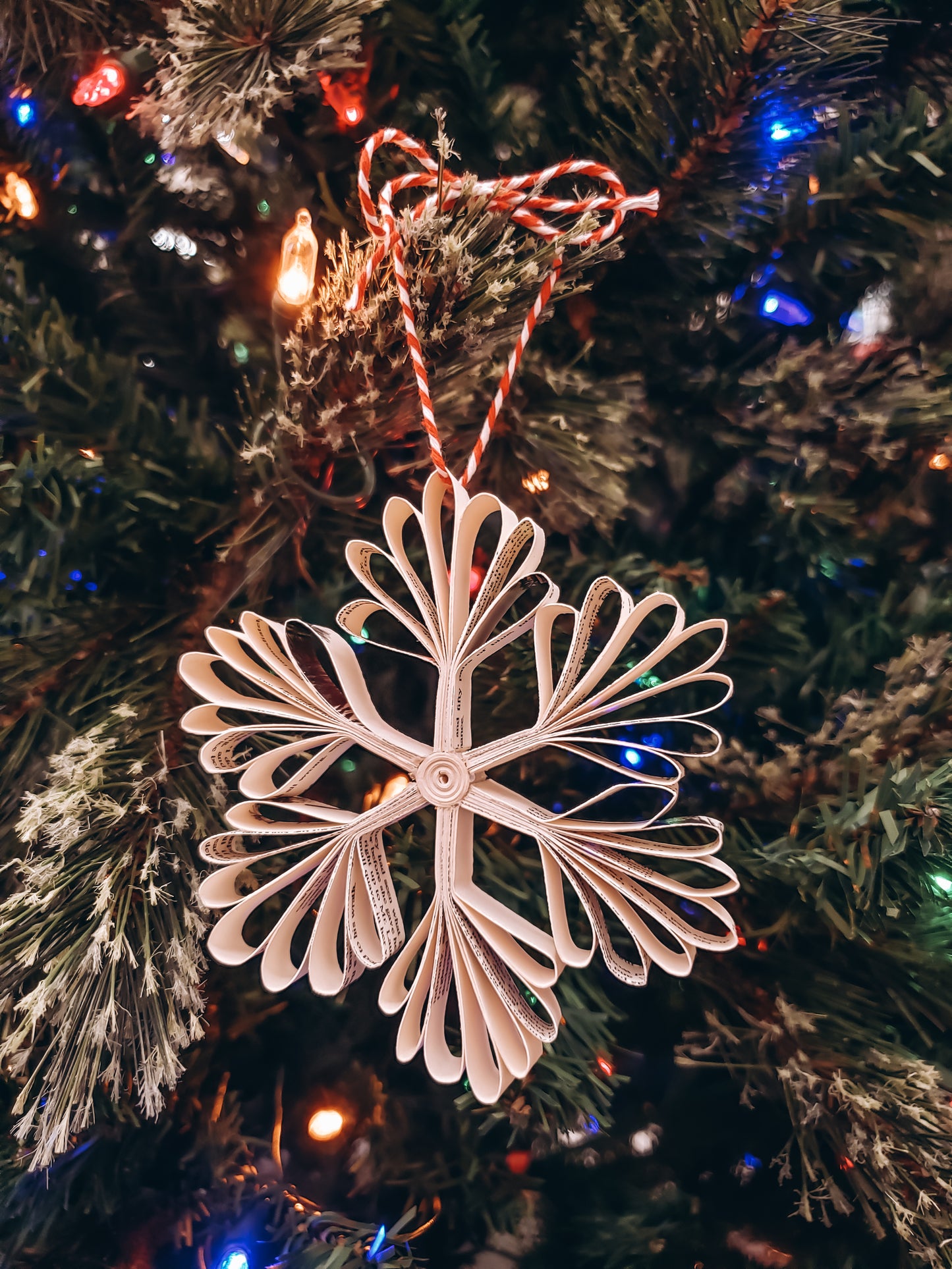 book page paper snowflake ornament on a tree - Novel Blossoms Co